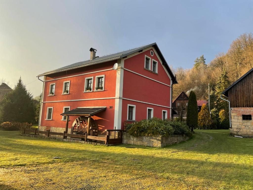 uma grande casa vermelha com um alpendre num quintal em Güntherův mlýn em Jetřichovice