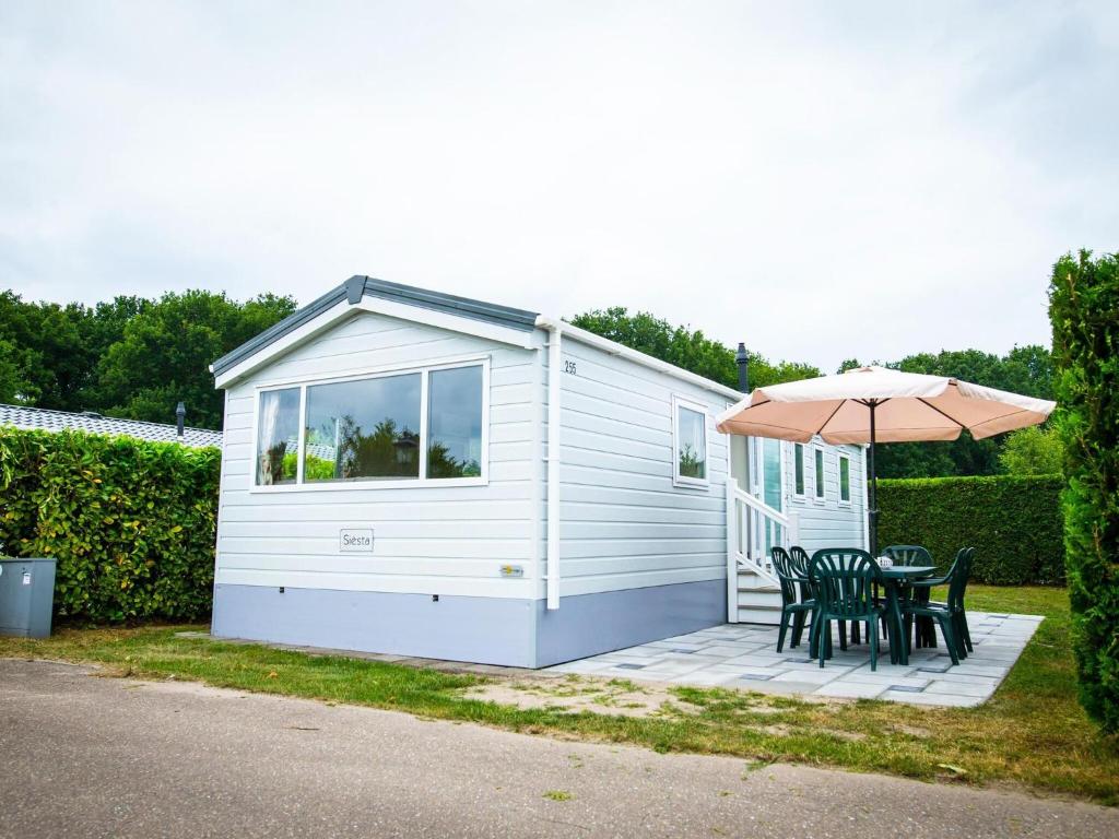 une petite cabine avec une table et un parasol dans l'établissement Recreatiepark Duinhoeve 12, à Udenhout