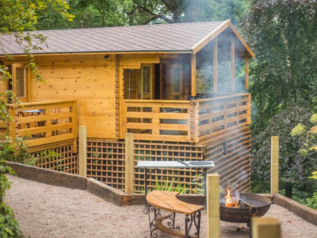 a wooden cabin with a grill and a fire pit at 1 Bed in Ironbridge 88768 in Leighton