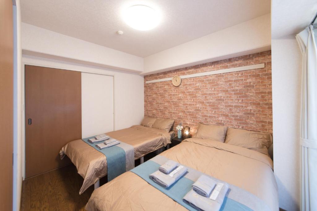Pokój z 2 łóżkami i ceglaną ścianą w obiekcie nestay apartment tokyo akihabara w Tokio