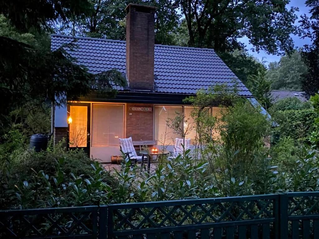 una pequeña casa con 2 sillas blancas en el patio en House in Appelscha on the edge of the forest, en Appelscha