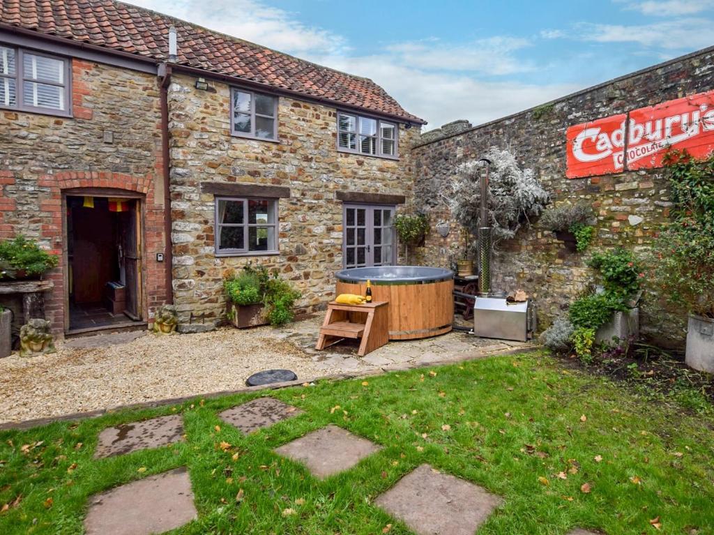 a garden in front of a brick building with a hot tub at 2 Bed in Frome 89168 in Holcombe