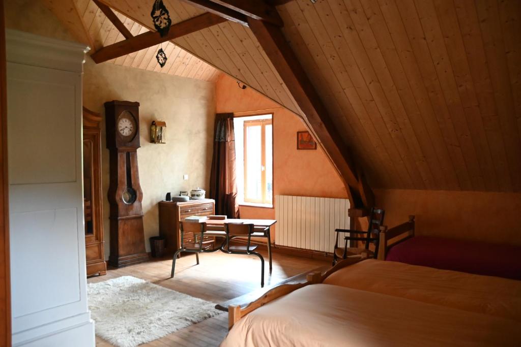 een slaapkamer met een bed en een tafel en een klok bij Le Deyran in Égliseneuve-dʼEntraigues