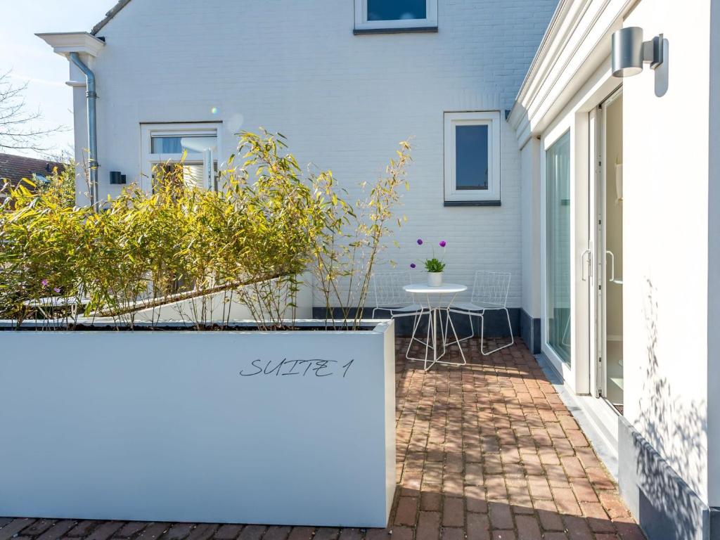 uma casa branca com uma mesa num pátio de tijolos em Pleasaing holiday home in Oostkapelle near centre em Oostkapelle