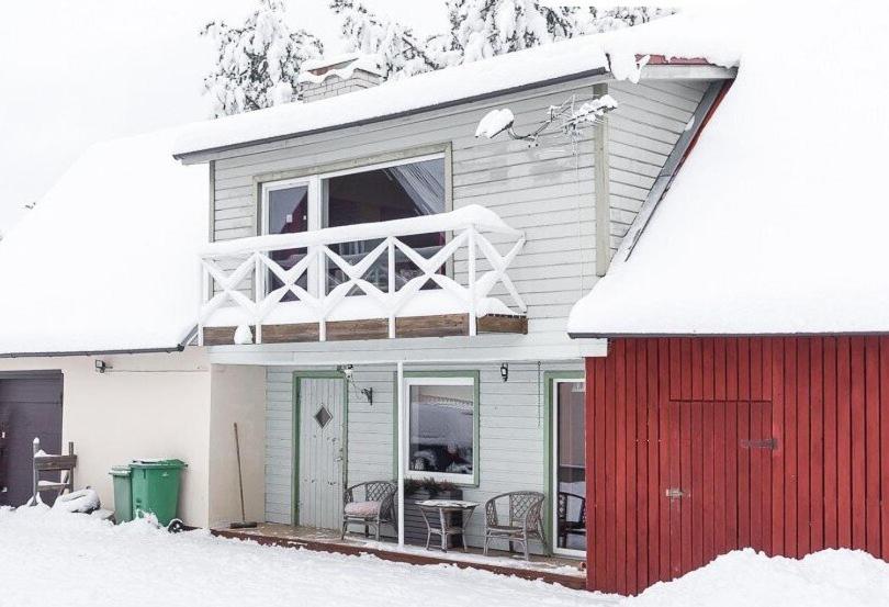 uma casa com uma porta vermelha na neve em Saadjärve Kingu talu puhkemaja em Valgma