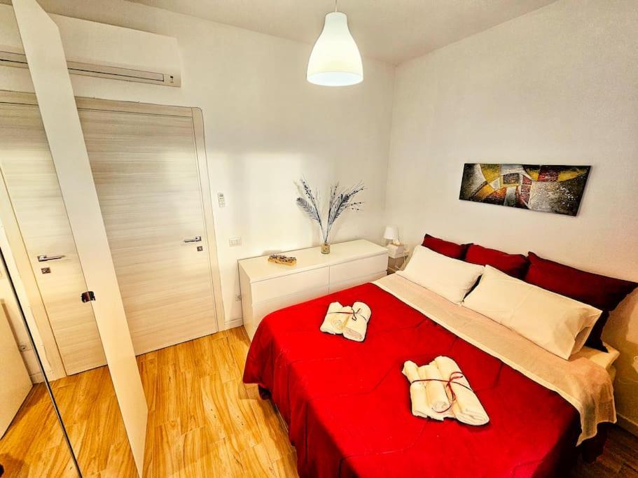 - une chambre avec un lit rouge et 2 serviettes dans l'établissement Appartamento a Pirri, via E. Toti. Cagliari. Rosas Rooms., à Cagliari