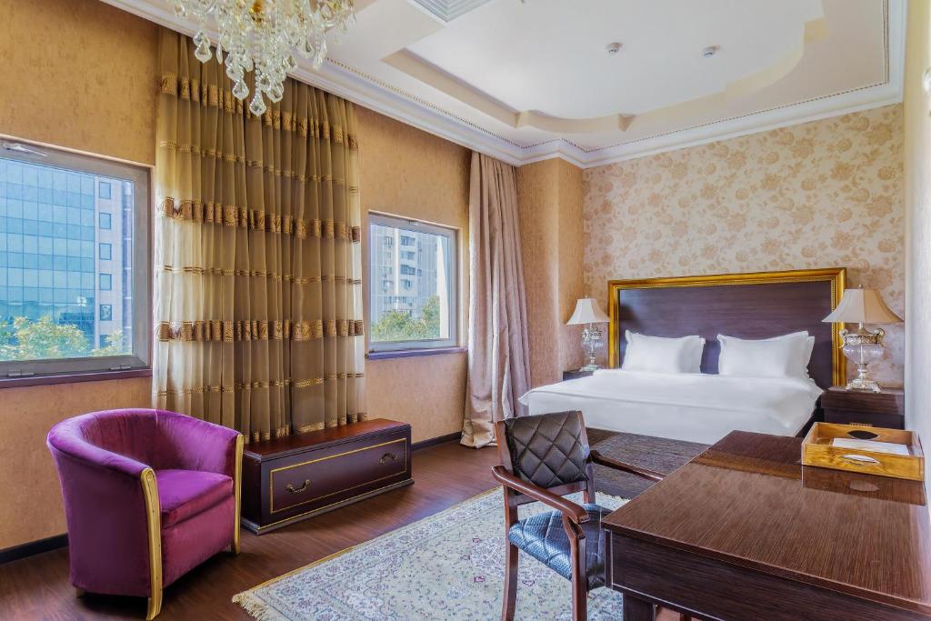 um quarto de hotel com uma cama, uma secretária e uma cadeira em Darhan Boutique Hotel em Tashkent