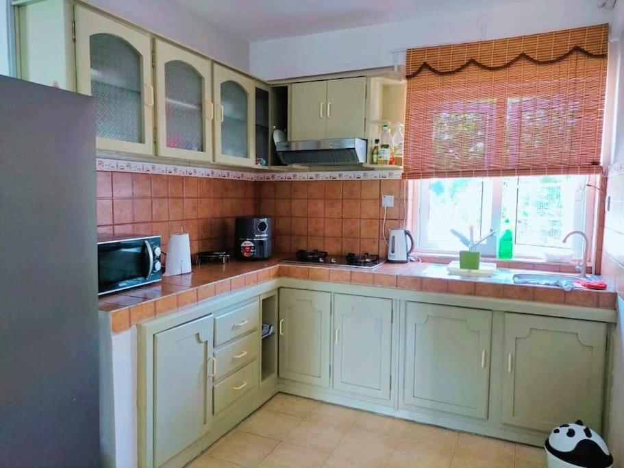 eine Küche mit grünen Schränken und einem Fenster in der Unterkunft Appartement calme à Calodyne proche de la plage in Calodyne