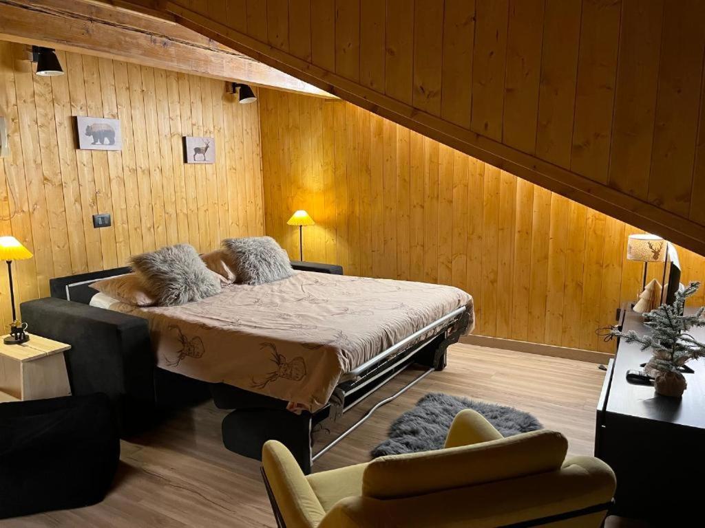 una camera con un letto in una stanza con pareti in legno di Mansarda delle Dolomiti nuovissimo appartamento a Madonna di Campiglio