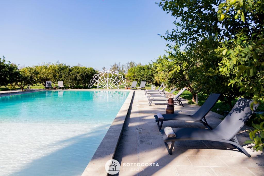 una fila di sedie seduta accanto alla piscina di Masseria Tenuta Le Menze a Cavallino di Lecce