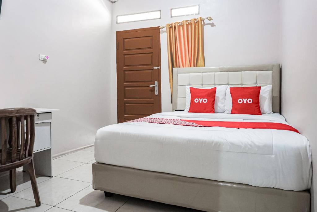 1 dormitorio con 1 cama con 2 almohadas rojas en OYO 93470 Bans Kostel, en Lampung