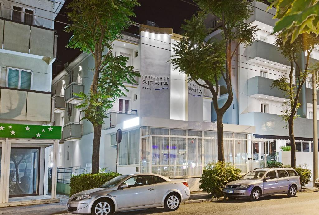 two cars parked in front of a building at Residence Siesta in Rimini