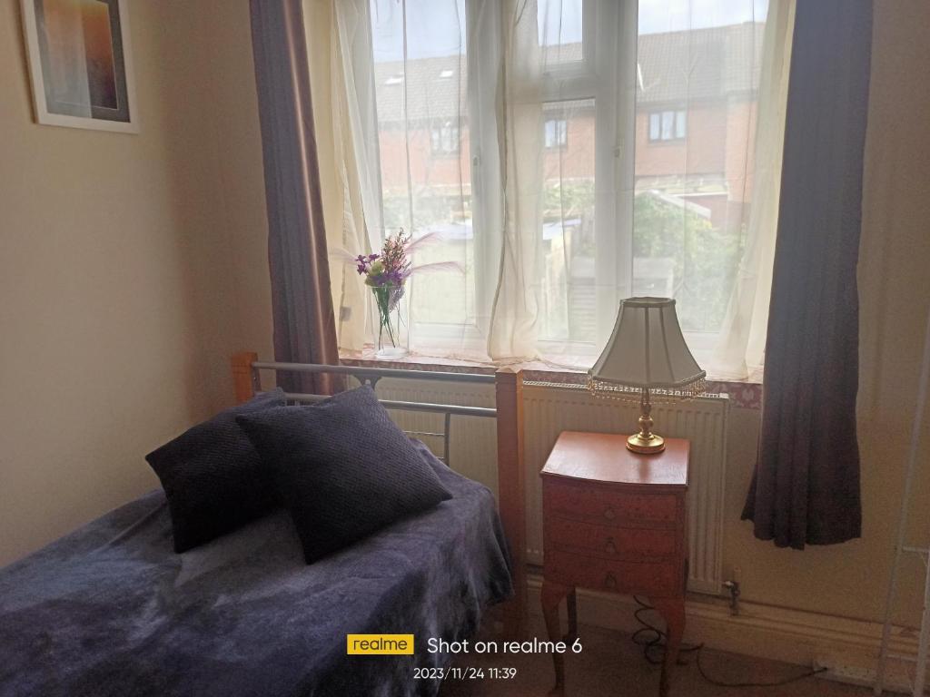 a bedroom with a bed and a window with a lamp at Goldy's place in E17 in London