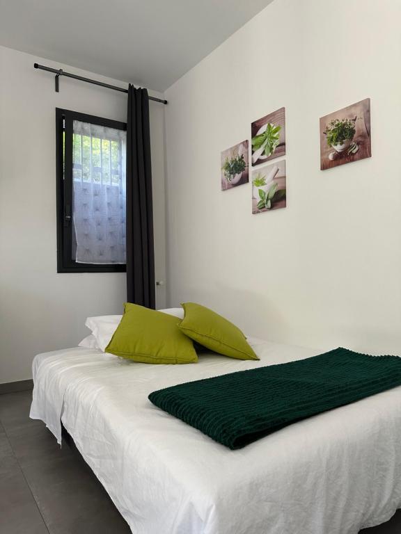 ein weißes Bett mit grünen Kissen und einem Fenster in der Unterkunft Case Costy in Aci Castello