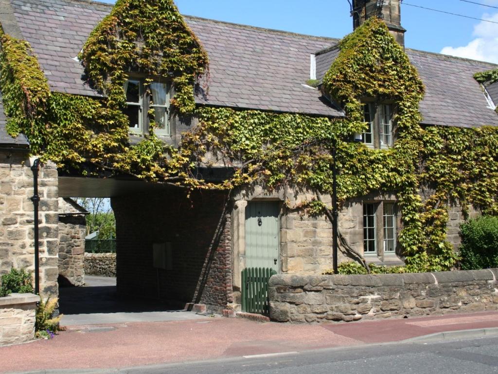 una antigua casa de piedra con una puerta verde en 3 Bed in Whitley Bay CN013, en Backworth