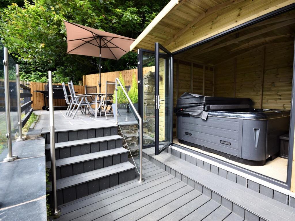 a deck with an outdoor grill and an umbrella at 3 Bed in Barnstaple 60511 in Swimbridge