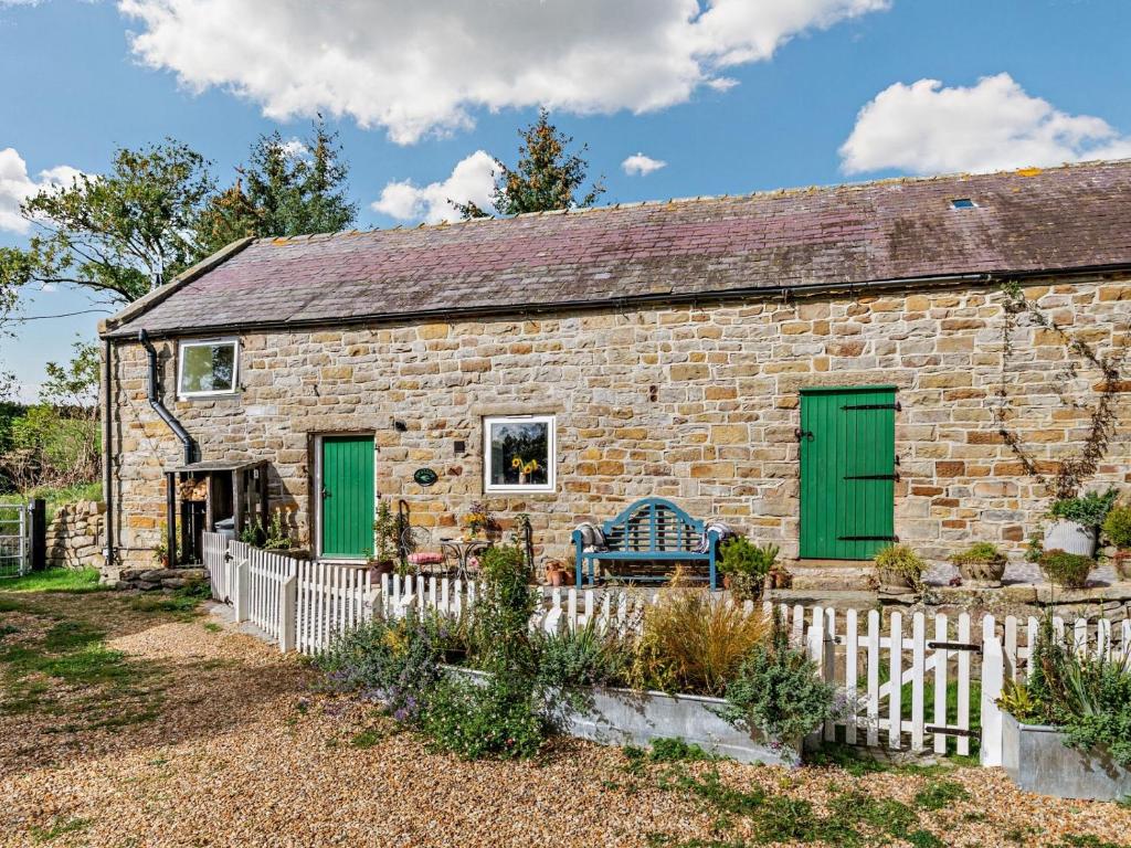 a stone cottage with green doors and a fence at 1 Bed in Robin Hoods Bay G0191 in Fylingdales