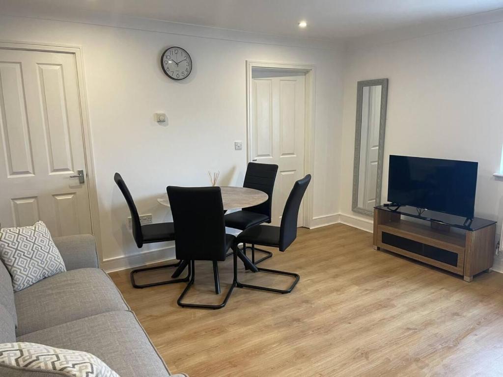 a living room with a table and chairs and a tv at Modern The Mews Apartment in Bury Saint Edmunds