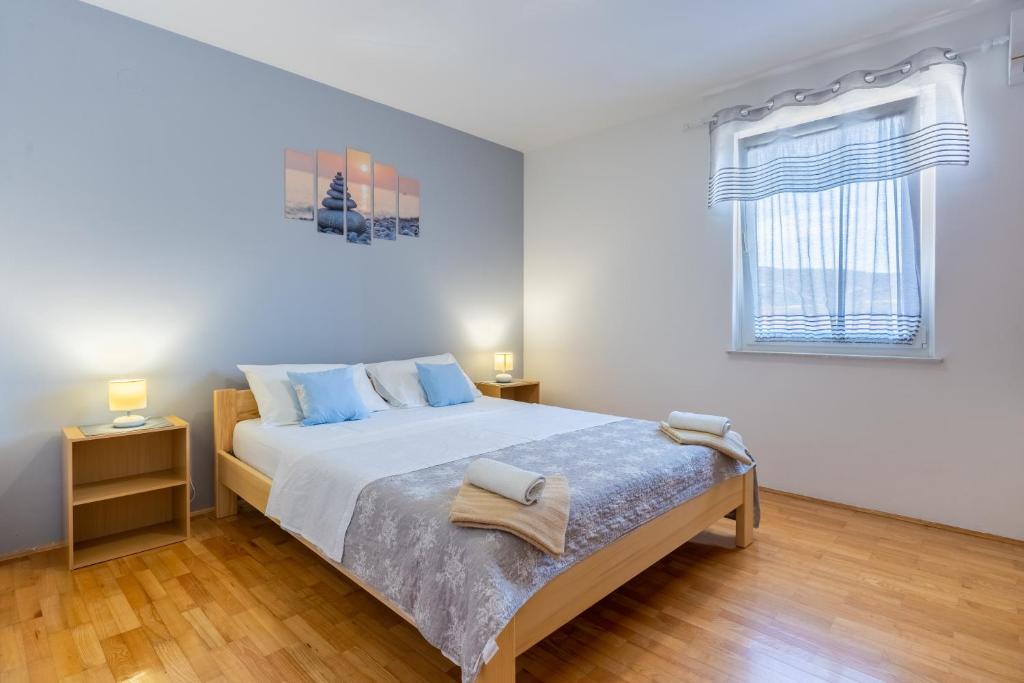 a white bedroom with a large bed with blue pillows at Apartment Kristian in Cres