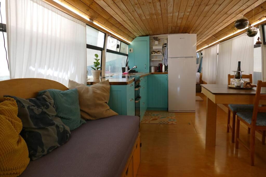 um quarto com um sofá e uma cozinha com um frigorífico em MashikaBus משיקה בס אירוח מפנק על גלגלים em Ta‘oz
