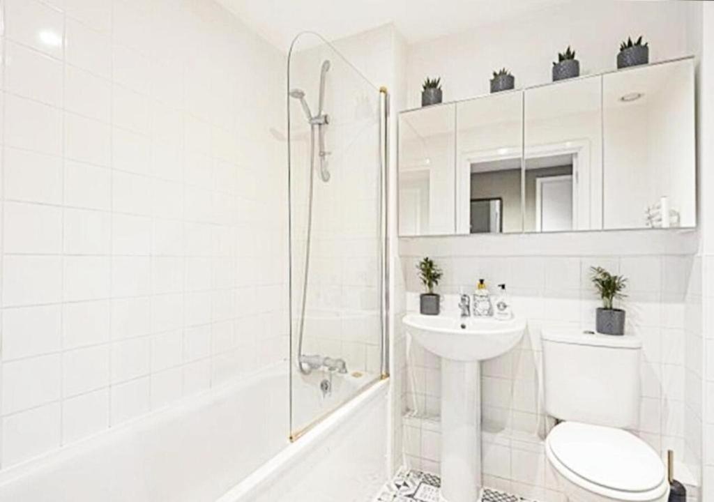 a white bathroom with a shower and a toilet and a sink at Your Riverside Home 3 with Private balcony in Woolwich