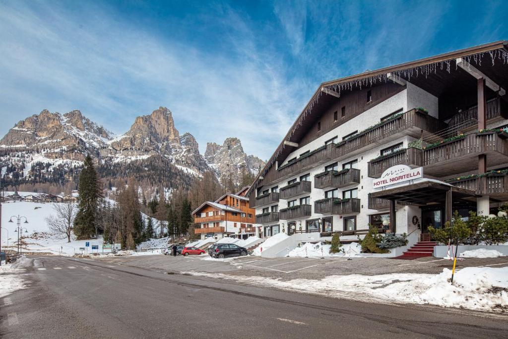 un hotel en las montañas con nieve en el suelo en Hotel Nigritella, en Selva di Cadore