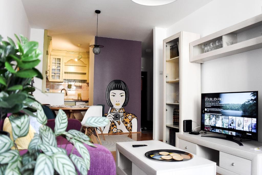 una sala de estar con una pintura de una mujer en La Maison, en Niš