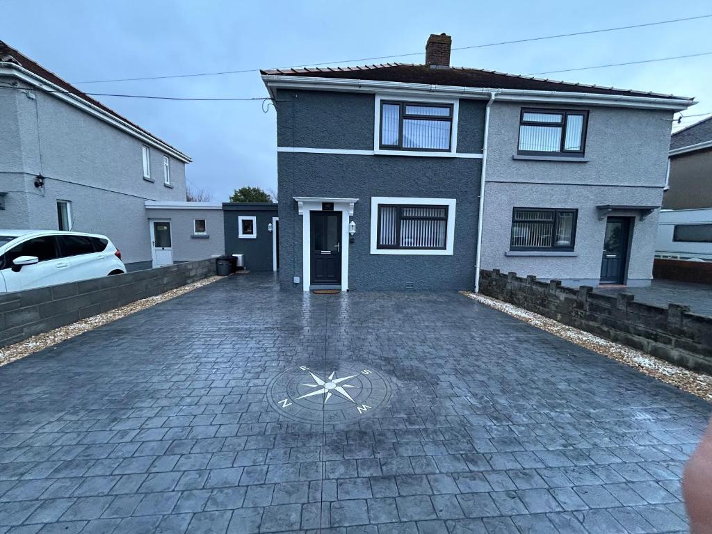 a house with a manhole in the middle of a driveway at Sŵn Y Môr in Burry Port