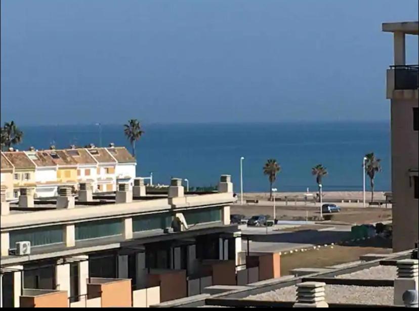 un edificio con un aparcamiento con palmeras y el océano en Piso acogedor con vistas al mar, en La Torre