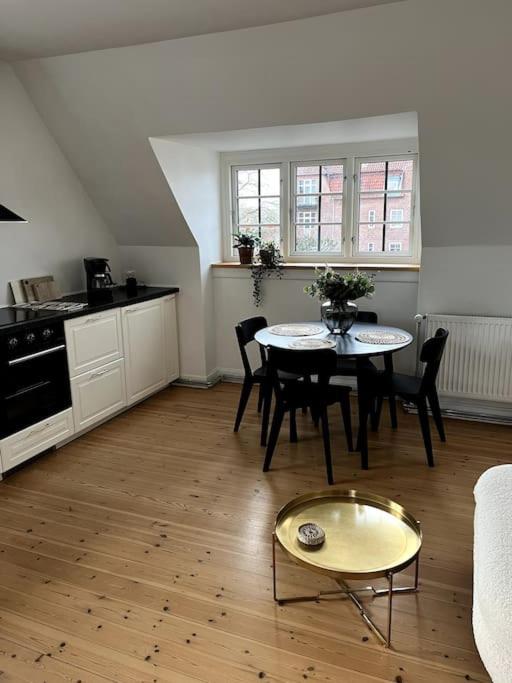 a living room with a table and a kitchen at Lys nyrenoveret lejlighed i Odense C in Odense