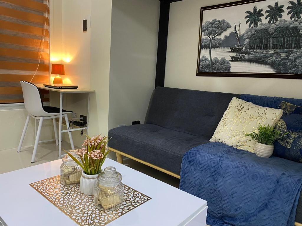 uma sala de estar com um sofá azul e uma mesa em Staycation w/ Free Pool at Victoria Sports em Manila