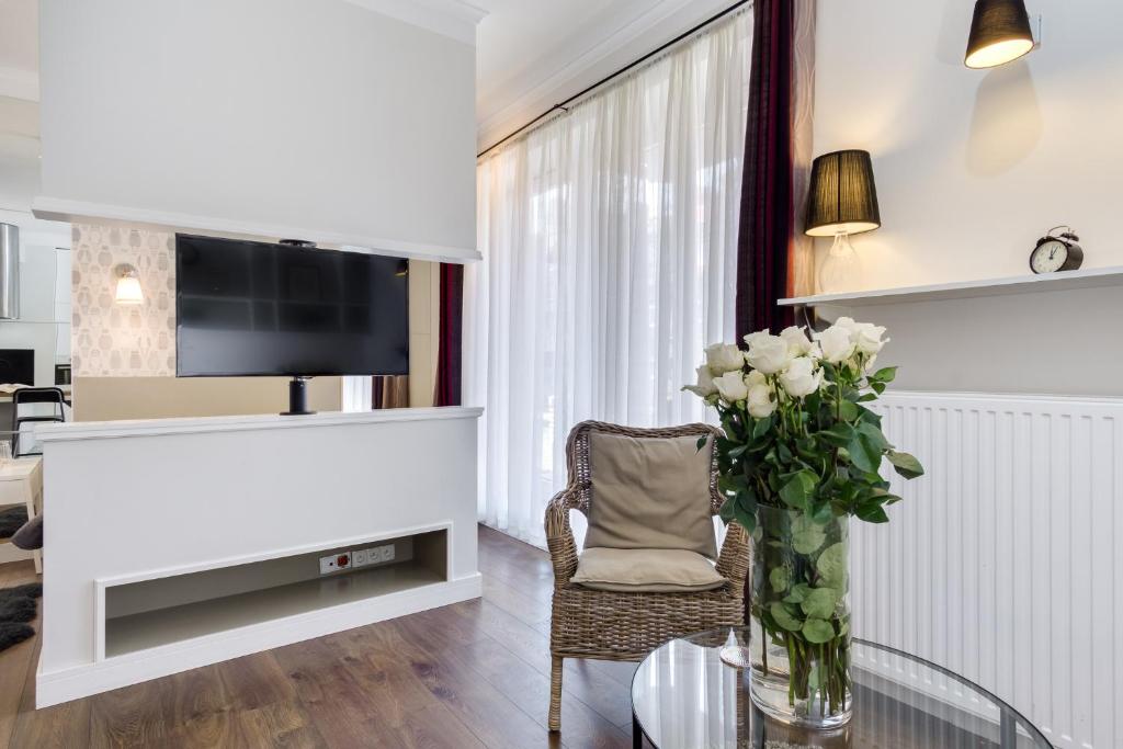 a living room with a glass table with a vase of flowers at Elite Apartments Kwartal Kamienic in Gdańsk