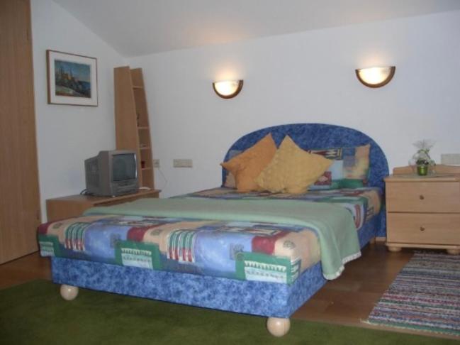 トゥクスにあるBärenklauseのベッドルーム1室(大型ベッド1台、青いヘッドボード付)