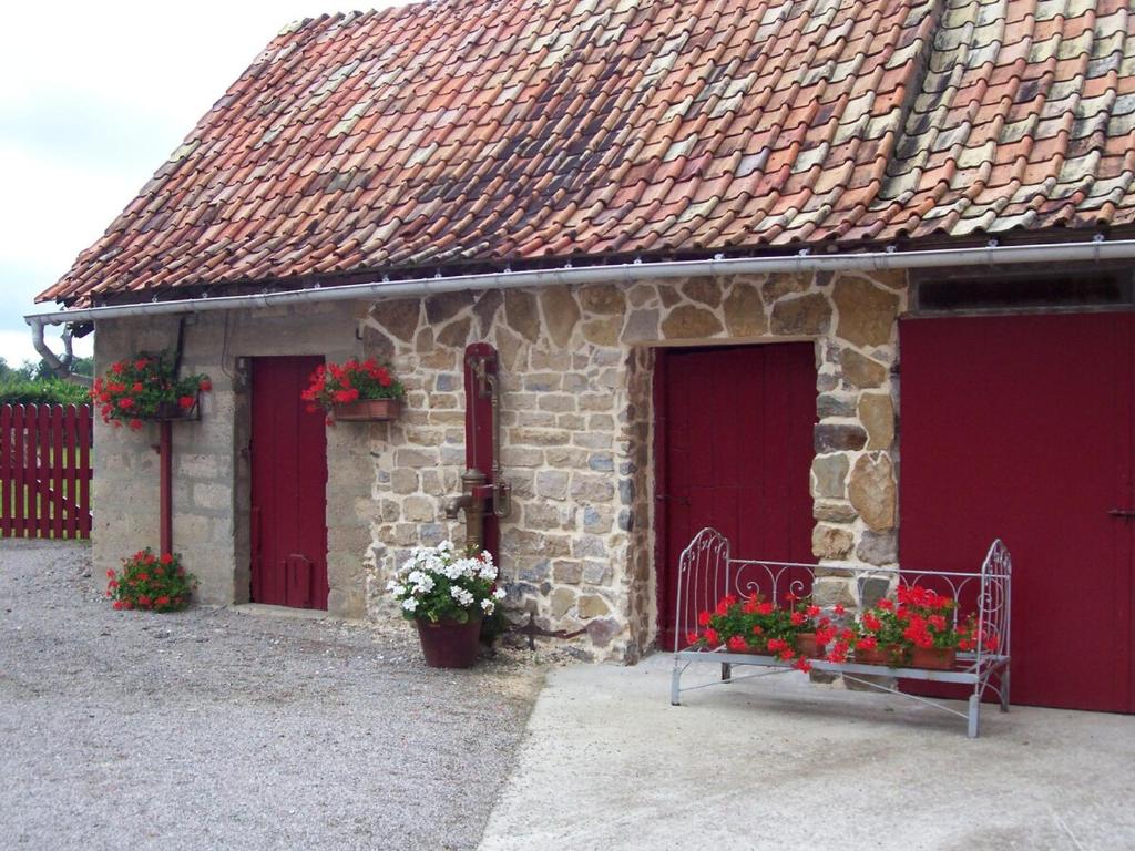 Henneveux的住宿－Le Gîte du Bois Groult，一座建筑,有两扇红色的门和花凳