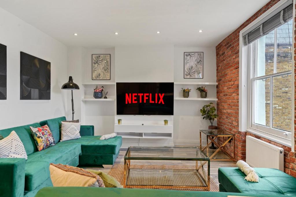een woonkamer met een groene bank en een tv bij Grand Flat in Little Venice - Sleeps 8 in Londen