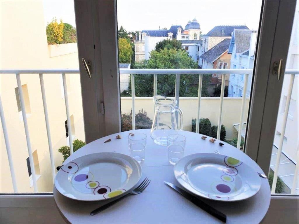une table blanche avec des assiettes et des verres sur un balcon dans l'établissement Royan - STUDIO LUMINEUX au calme - 30m de la PLAGE - Quartier du PARC, à Royan