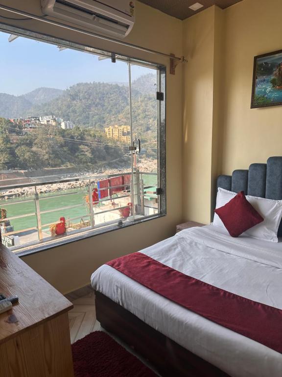 ein Schlafzimmer mit einem Bett und einem großen Fenster in der Unterkunft The Peninsulla in Rishikesh