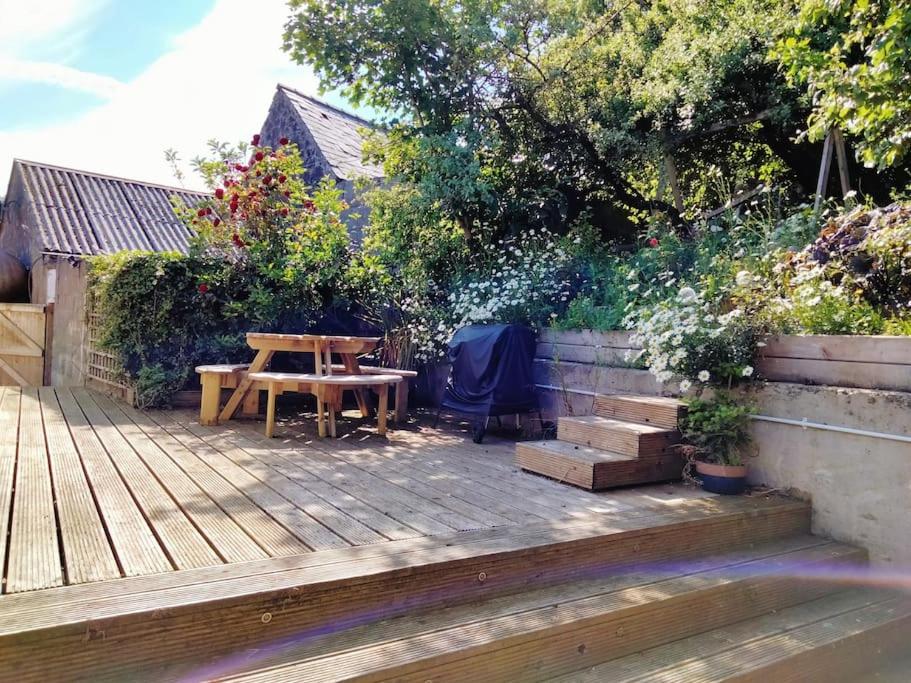 a wooden deck with a wooden table and a picnic table at Midden Manor: Farm stay in rural County Antrim. in Cullybackey