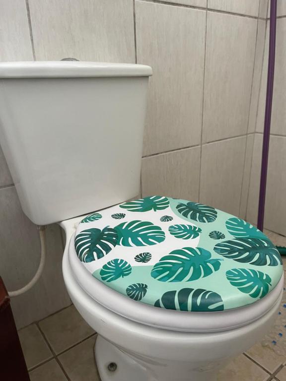 a toilet seat with a green leaf pattern on it at 03 Doutor Hostel 800mts da praia in Guarujá