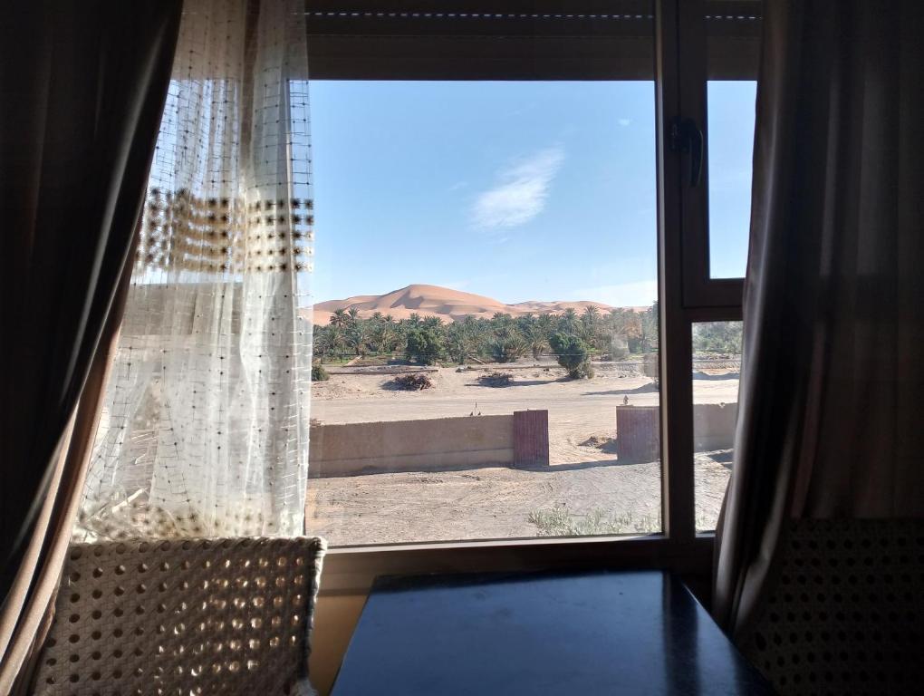 ein Fenster mit Blick auf die Wüste in der Unterkunft Auberge L'oasis in Merzouga
