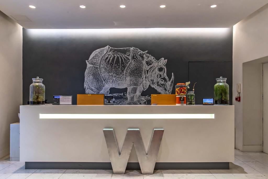 a lobby with a counter with a w sign and vases at Hotel White in Rome