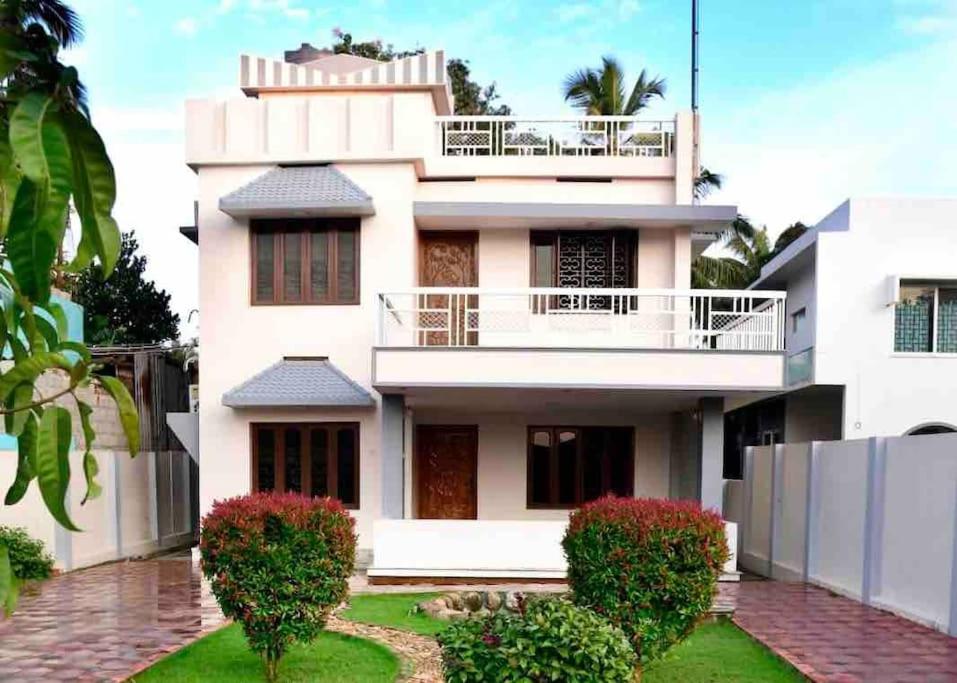 a white house with a balcony on top of it at Spacious Guesthouse in Nagercoil in Nāgercoil
