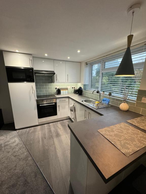 a large kitchen with white cabinets and a sink at modern 1 bed apartment with car parking in Bitton