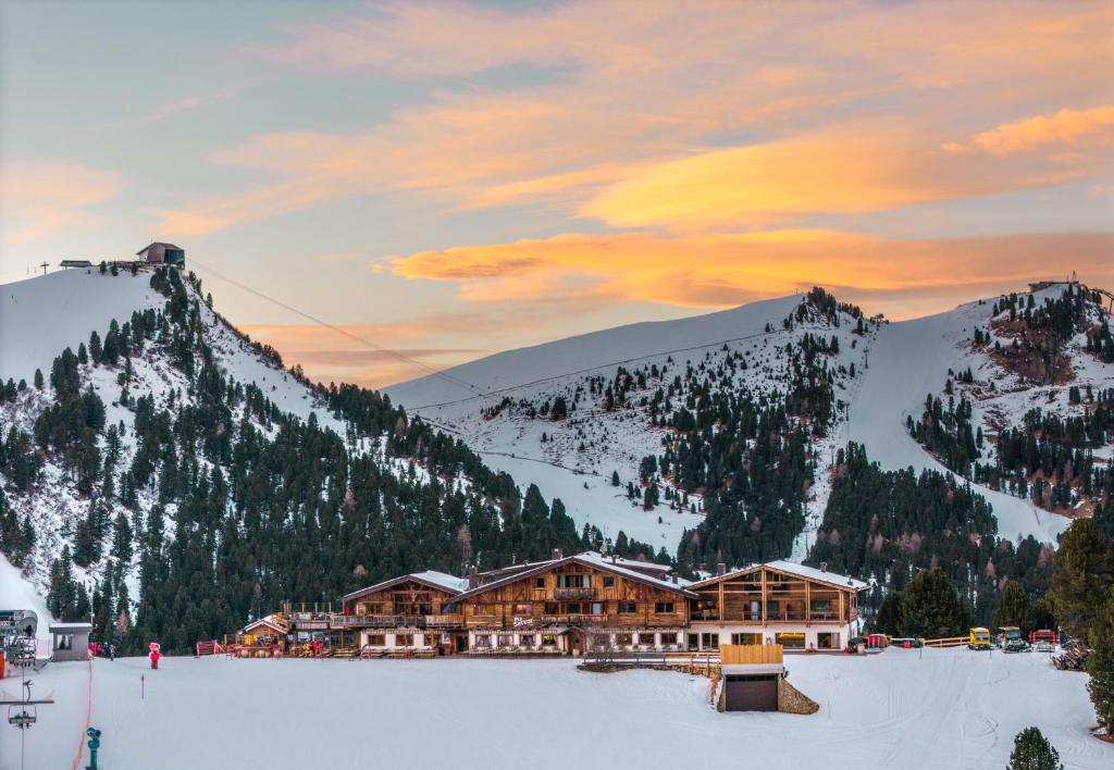 eine Skihütte im Schnee mit einem Berg in der Unterkunft Hotel Piz Seteur in Wolkenstein in Gröden