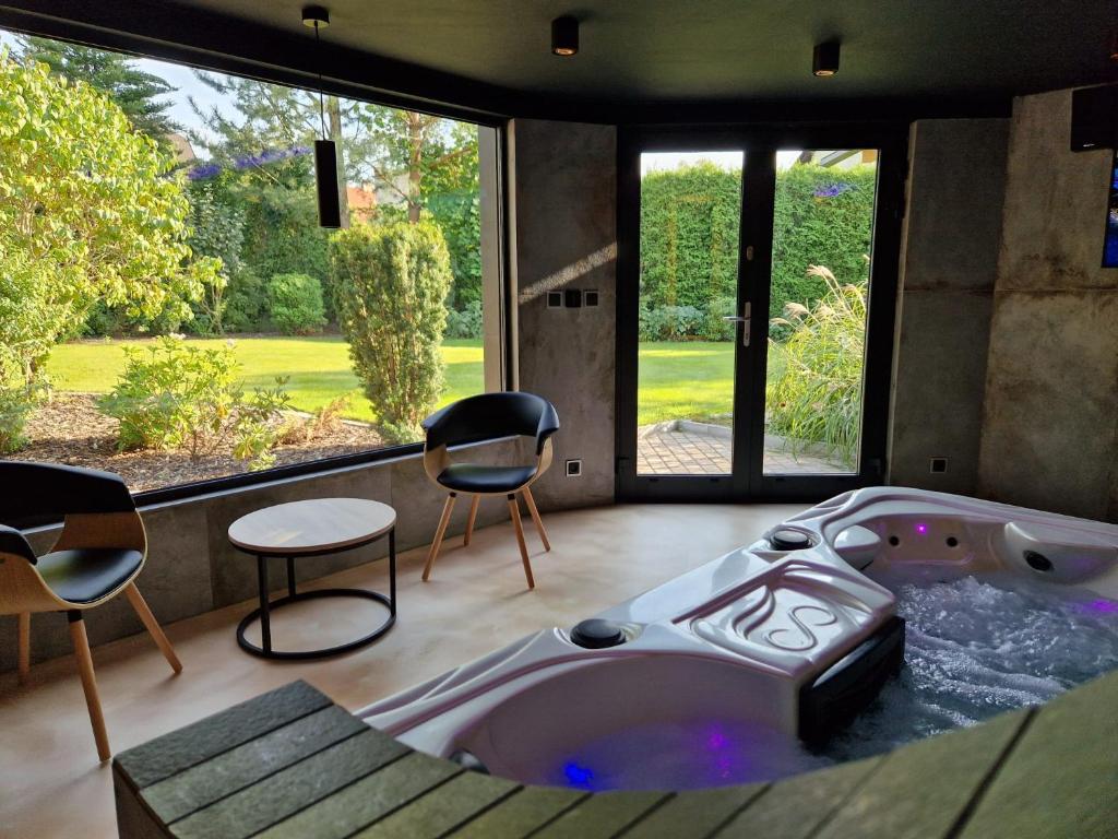 eine große Badewanne in einem Zimmer mit Stühlen und Fenstern in der Unterkunft Relax Vila se zahradním wellness in Ostrava
