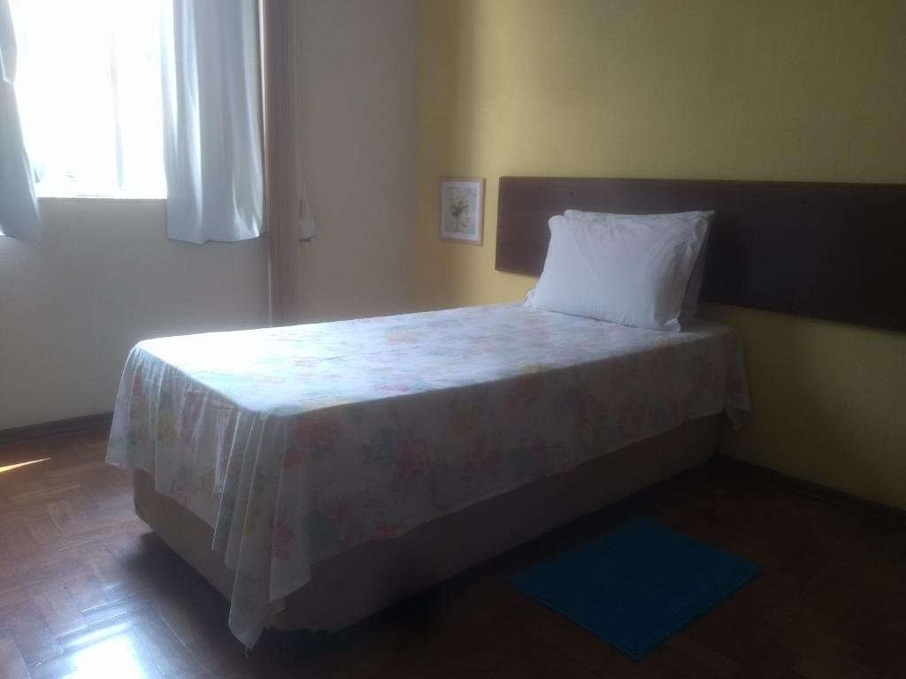 1 dormitorio con cama con almohada y ventana en Apartamento Várzea, en Teresópolis