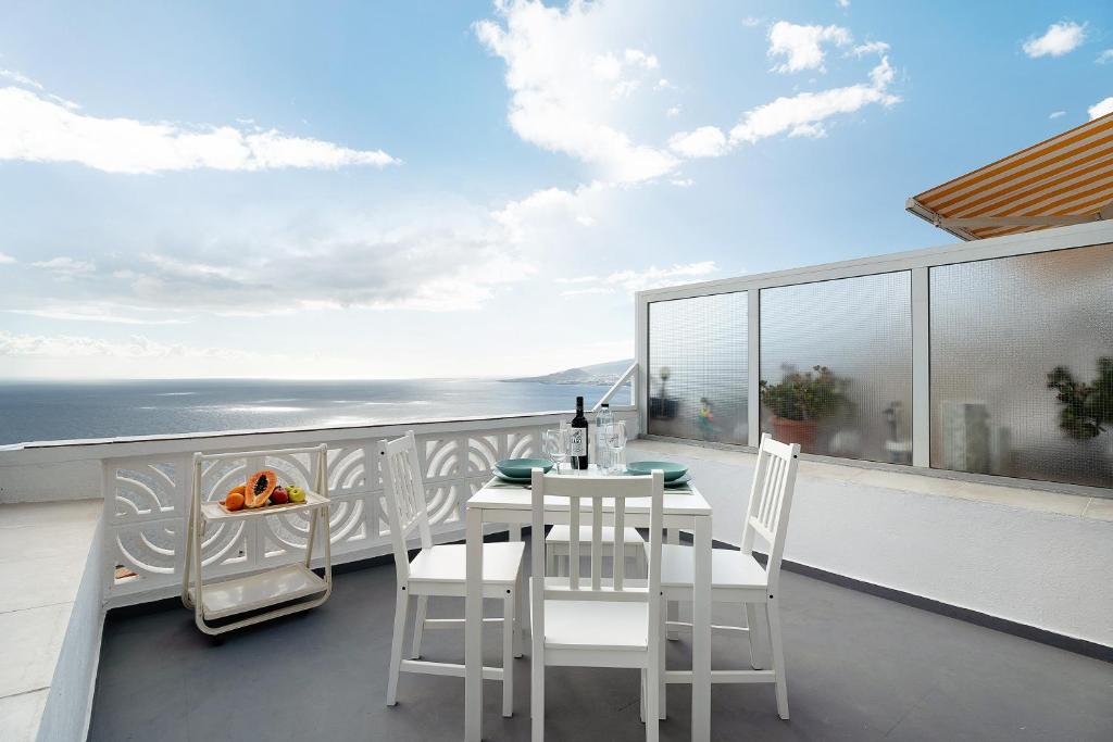圣克鲁斯-德特内里费Apto Las Florita By Paramount Holidays的阳台上有一张白色的桌子和椅子，可以欣赏到大海