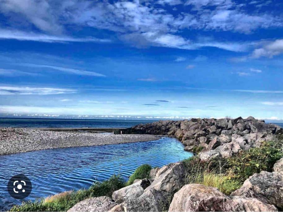 a river on the shore of a rocky beach at Luxurious 2 Bedroom Private Detached Cottage in Llanddulas