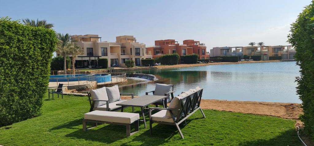 una mesa y sillas junto a un río con edificios en Luxury 3BR Townhouse, Tawila, El Gouna, Lagoon & Pool access en Hurghada