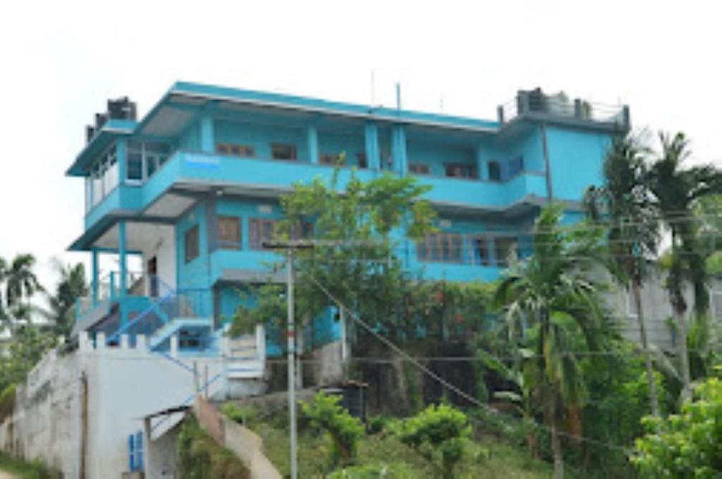 a blue building on top of a hill with trees at Pramod Bhawan , Port Blair in Port Blair